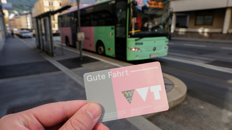 Eine Hand h&auml;lt ein Klimaticket. Im Hintergrund sieht man einen Bus. 