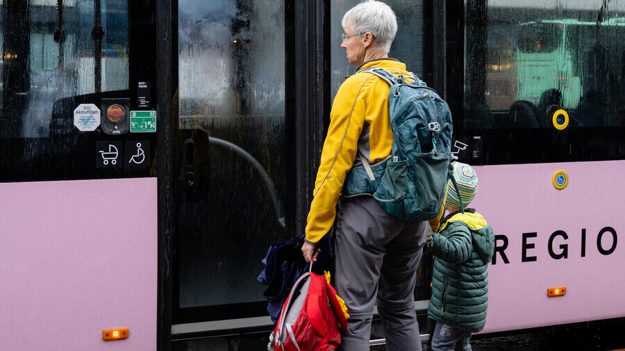Eine Erwachsene und ein Kind warten auf den Bus.