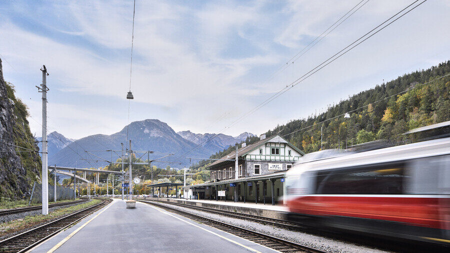 Es ist der Bahnhof Imst Pitztal zu sehen mit einem unscharfen Zug, welcher losfährt. 